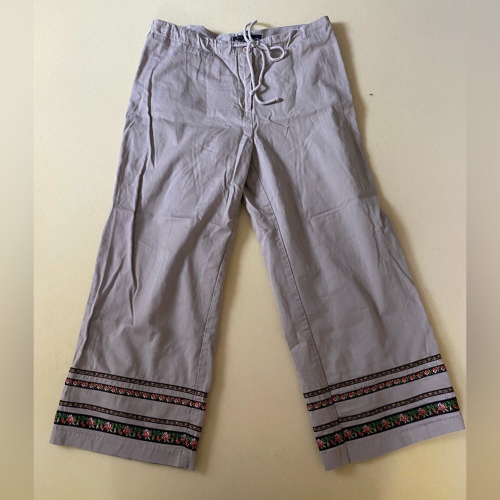Tan flare pants with black, pink, and green rose designs along the ankle